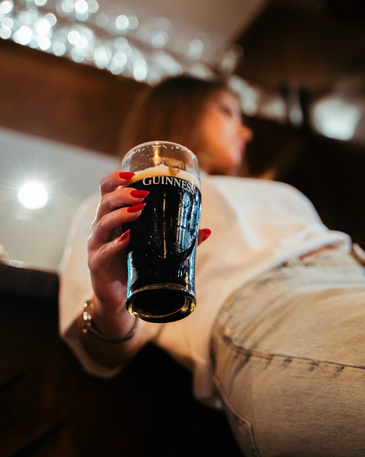 Ragazza con pinta al banco, luci bokeh — atmosfera Domas Pub Torvaianica