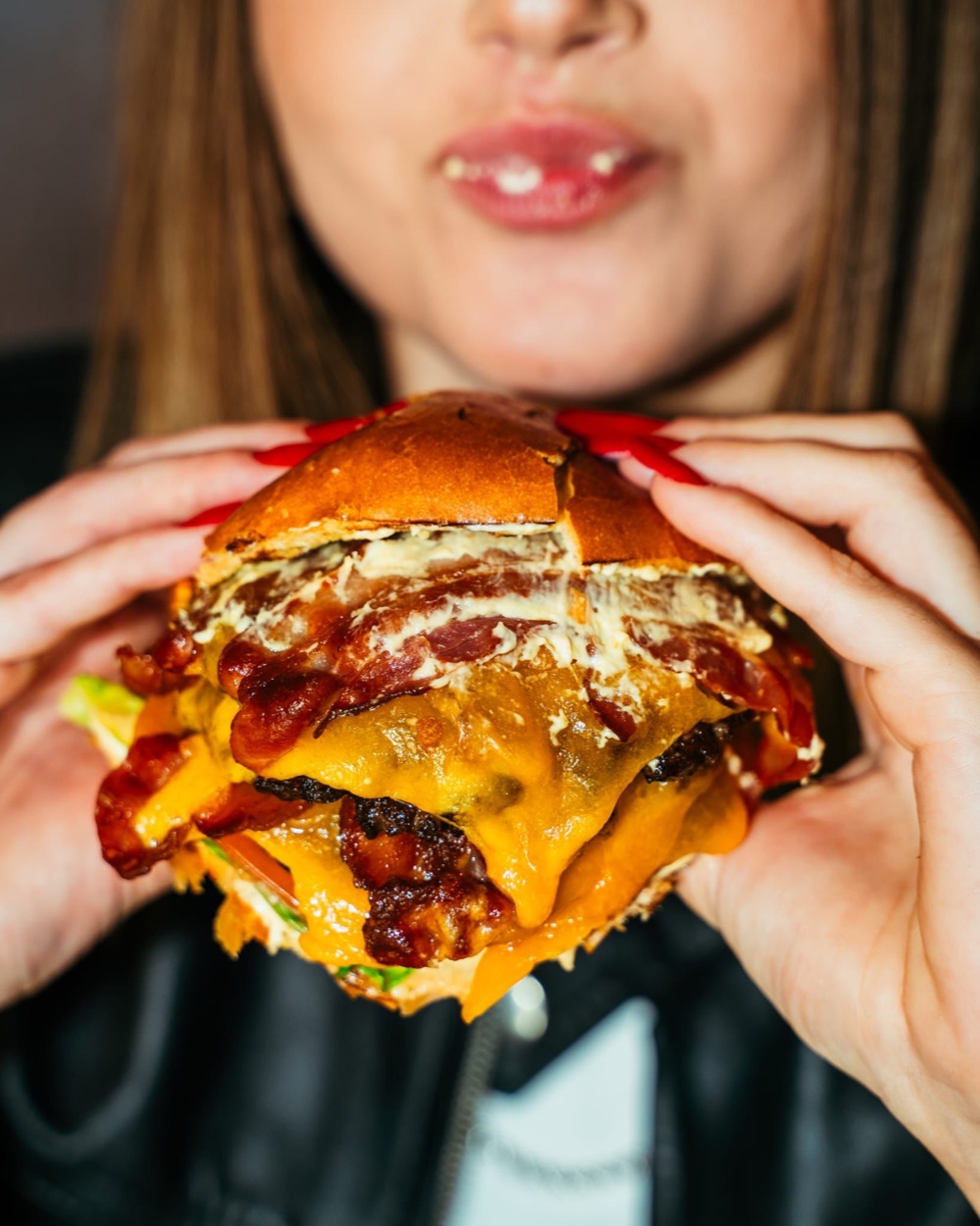 Doppio burger con cheddar e bacon tenuto a due mani, Domas Steakhouse
